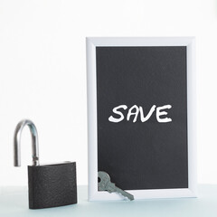 In a black-and-white frame, the inscription save. Next to the frame is an open lock and key.