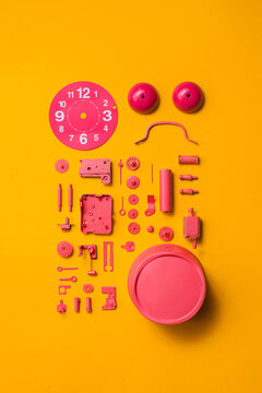 Organised Disassembled Clock/pink parts on orange background
