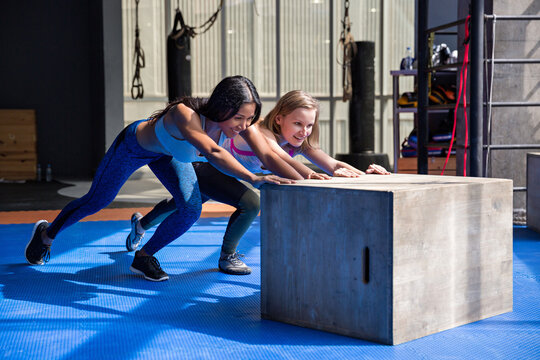 Two workout friends pushing a plyo box