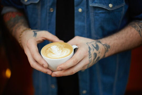 Male tattooed hands holding a cup of coffee