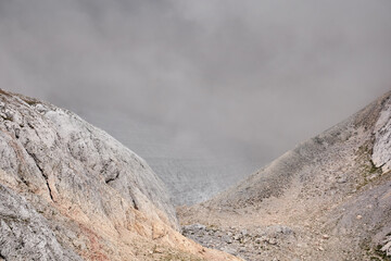 gloomy alpine canyon partially obscured by a cloud