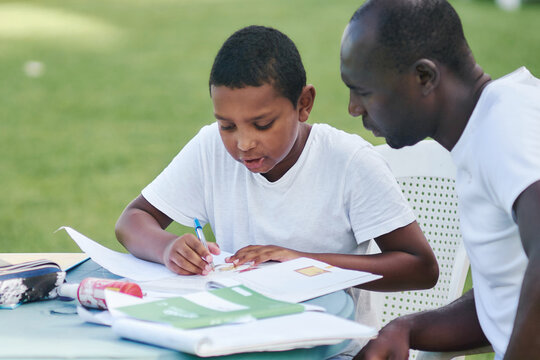 Father and son doing schoolwork together outdoors