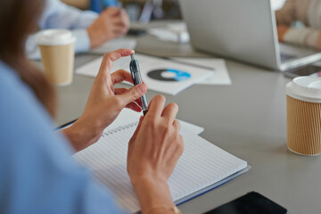 Close crop of nervous business woman hands holding pen during meeting