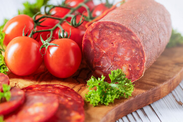 Chorizo sausage. Spanish traditional chorizo sausage with fresh tomatoes.  Served on an olive plate.