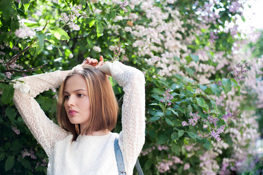 Portrait of young woman among lilac in blossom