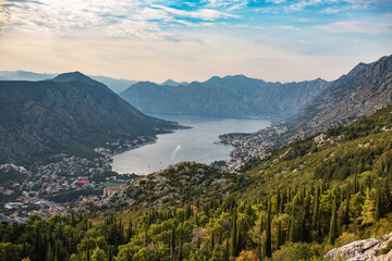 Fototapeta na wymiar Panorama of Kotor bay and city from mountain road. Picturesque view to Kotor city with lovely architecture and beautiful mountains of Montenegro at sunset.