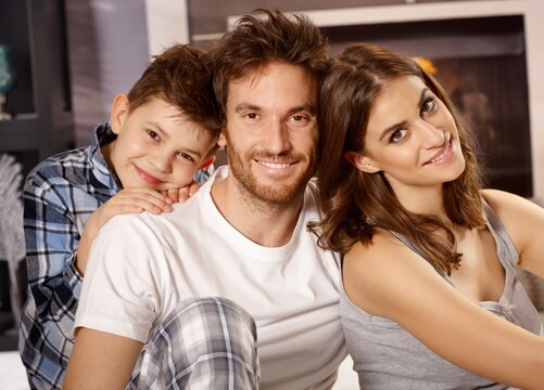 Closeup portrait of happy young family with little boy, smiling, looking at camera. 