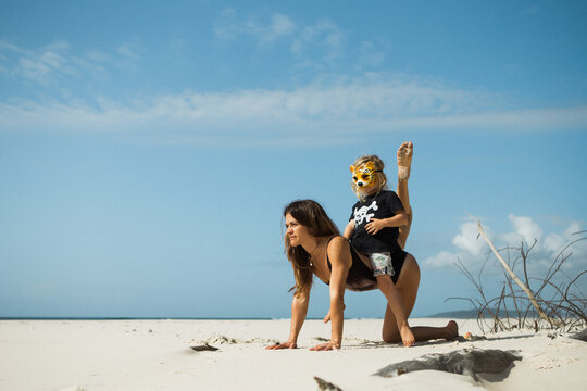 Mother and son wearing a tiger mask playing on an empty beach