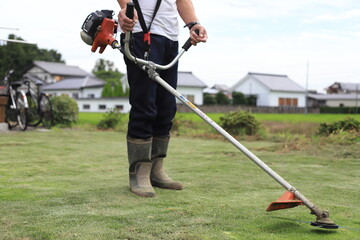 芝刈り機で庭の雑草を刈っている男性