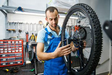 Bicycle assembly in workshop, man setting up chain