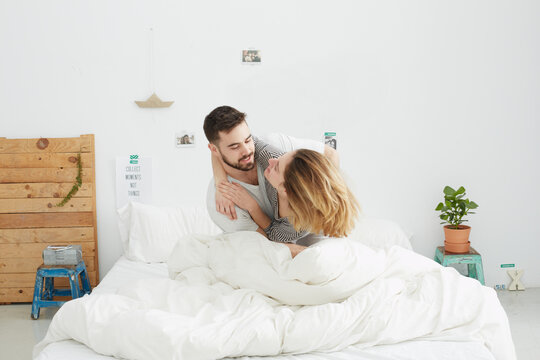 Young couple in a loft bedroom playing and embracing