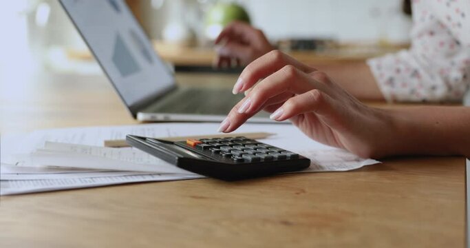 Close up woman accountant working using calculator and laptop, graphs statistics on device screen. Make payments on-line through secure bank system, analyze company charges calculate expenses concept
