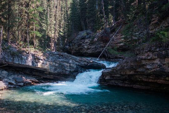 A small waterfall pours over a shale ledge in a forest