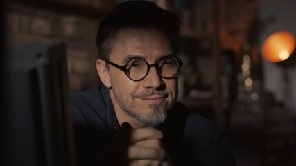 Obraz premium Facial portrait of mature man in his 50s at home sitting in dark living room, thinking. 