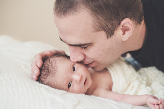 Father gently kissing his newborn baby's face