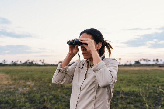 Woman animal watching in binoculars on African safari