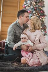 Happy family near christmas tree open gifts in daytime. Mother father and daughter