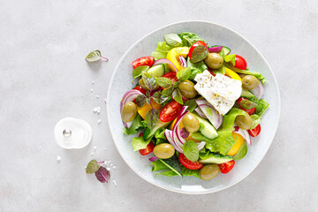Greek salad. Fresh vegetable salad of cucumbers, tomatoes, olives, onion, bell pepper, feta cheese, lettuce and herbs and dressed with salt, pepper and olive oil. Horiatiki salad