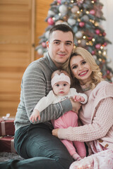 Happy family near christmas tree open gifts in daytime. Mother father and daughter