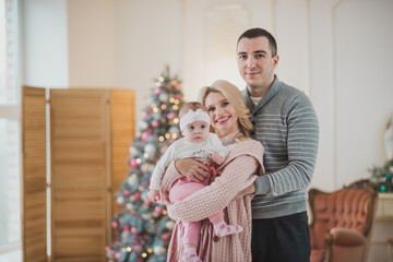 Happy family near christmas tree open gifts in daytime. Mother father and daughter