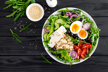 Greek style healthy breakfast bowl with oatmeal porridge and fresh vegetable salad of lettuce, arugula, olives, tomato, cucumber, feta cheese and boiled egg