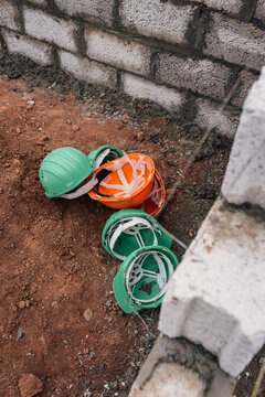 Green and orange safety hard hats on ground for charity