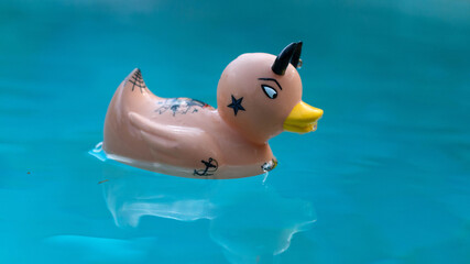 un canard de bain tatoué à l'allure originale qui flotte dans une piscine.