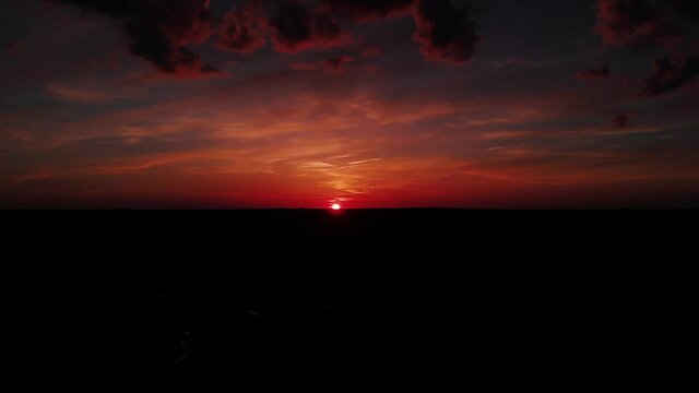 Vibrant, red and orange sunset from aerial drone footage over wild terrain in Iowa.