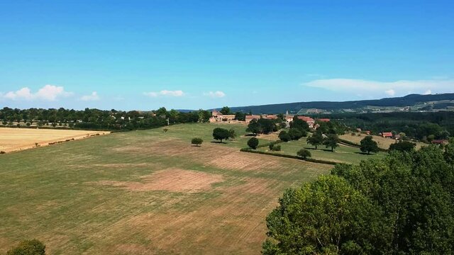 Slow forwards moving drone shot of wheat fields, near small village Taize in France.