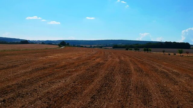 Fast backward moving shot of a field, brown color, near Taize village in France.