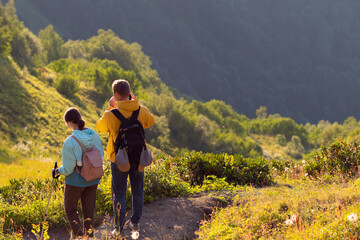 Obraz premium Tourists admire the landscape in the mountains. Golden rays of the evening sun