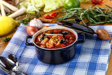 Solyanka soup with meat, sausage, vegetables, olives and lemon is poured into a plate,