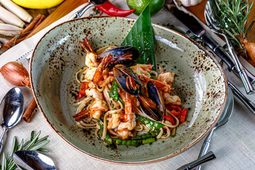 Egg noodles with seafood, shrimp, squid and mussels in tomato sauce on a plate, Asian cuisine