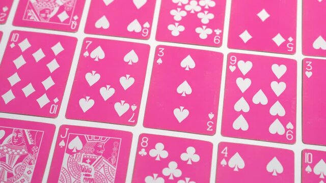 Smooth sliding shot of a set of pastel pink color poker card on a white background in 4K