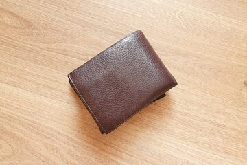Men's brown leather wallet on a wooden table. Top view, flatlay