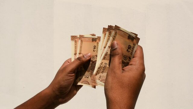 Hands of a man counting new Indian 10 Rupee Currency Notes.