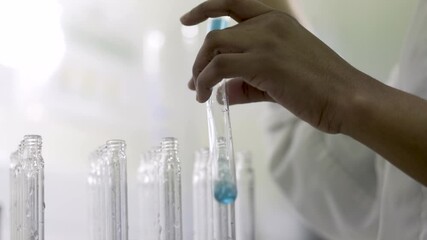 A lab technician fills a test tube with blue solution.