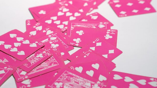 Pushing a pile of pastel pink color poker card onto a white surface in 4K