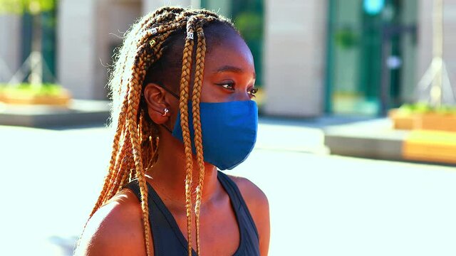 a snotty afro girl stands on the street wearing a mask during the coronavirus.