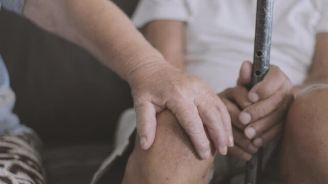 cinematic shot of an elderly couple sitting on a sofa holding hands