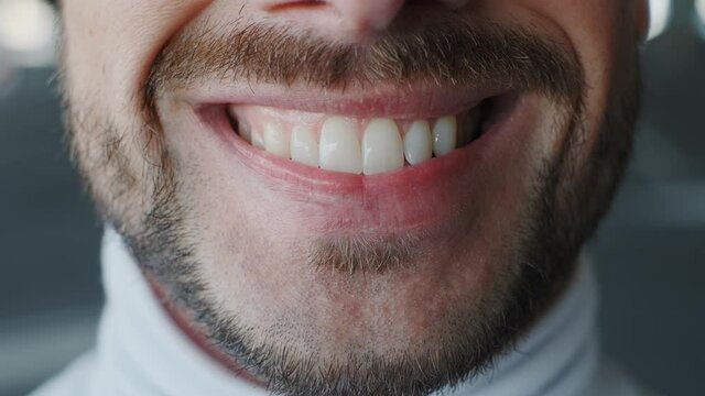 Close up of smiling teeth isolated. Detail of a smile bearded man. Young successful man is smiling on bokeh background.
