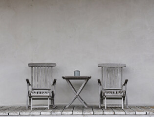 closeup of a grey table against a grey wall with a grey pot with stone on the top.