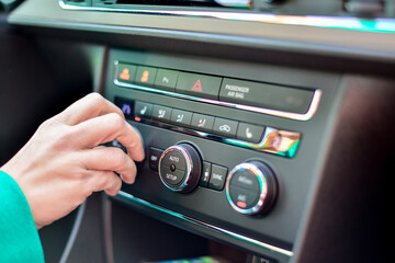 a woman's hand adjusts the climate control in the car
