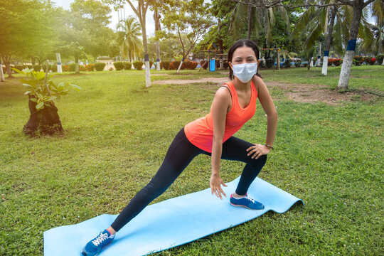 Woman with mask doing yoga in the park