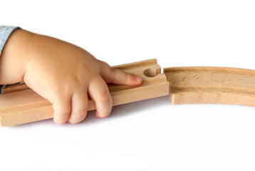 A child builds a railway out of wood. Close-up of a child's hand.