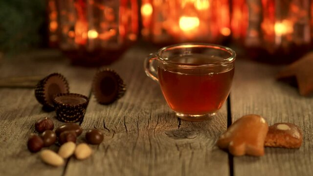 Homemade Christmas mulled wine punch with gingerbread, nuts and sweets on wooden rustic table in 4K VIDEO. Burning candles in background. Traditional autumn and winter hot drink. Close-up.