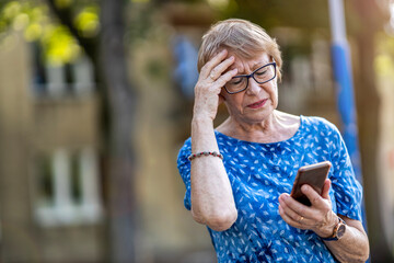 Stressed senior woman using mobile phone outdoors