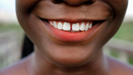 Fototapeta premium cheerful young African-American woman face with bright red lipstick smiles against blurred background extreme close view