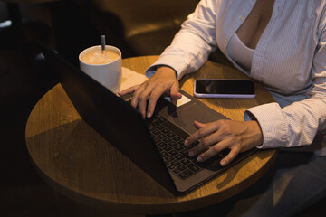 Fototapeta na wymiar Caucasian woman in a coffee shop working with a laptop while talking on the phone and had a coffee
