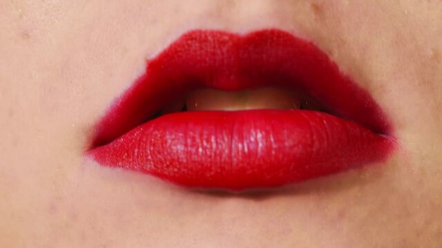 CLOSE UP, red lips blowing cigarette smoke at the camera